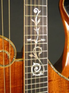The inlay uses a scroll motif found in many historical harp guitars. The two doves at the 12th fret symbolize peace and music.